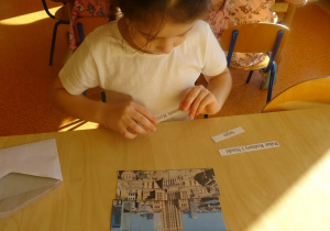 Dziewczynka dopasowuje do ułożonego obrazka z części podpis.
